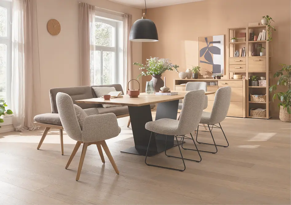 Esszimmer mit Holztisch, vier gepolsterten Stühlen und Regal, Fenster links und Pendelleuchte über dem Tisch